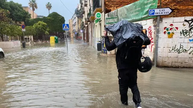 epa11718610 A man walks in a flooded street in Malaga, Andalusia, Spain, 13 November 2024. Water and hail storms in Malaga have resulted in flooding and the formation of enormous pools of water on some of the city's main streets. Malaga is on red alert for extreme risk owing to the expected heavy rainfall. EPA/MONTSERRAT MARTINEZ