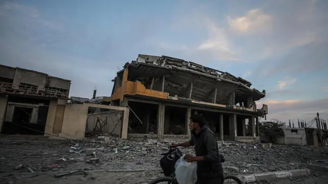 epa11715355 A Palestinian man pushes a bicycle past a destroyed building in the west of Al Nuseirat refugee camp, central Gaza Strip, 11 November 2024. More than 43,600 Palestinians and over 1,400 Israelis have been killed, according to the Palestinian Health Ministry and the Israeli Army, since Hamas militants launched an attack against Israel from the Gaza Strip on 07 October 2023, and the Israeli operations in Gaza and the West Bank which followed it. EPA/MOHAMMED SABER