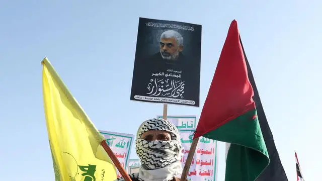 epa11723145 A Houthi supporter wears a traditional Palestinian keffiyeh and holds an image of late Hamas leader Yahya Sinwar and the flags of Palestine and Hezbollah group, during an anti-USA and anti-Israel protest in Sana'a, Yemen, 15 November 2024. Thousands of Houthi supporters rallied in Sana'a against the US support for Israel's military operations in Lebanon and the Gaza Strip, amid escalating tensions over the Houthis' maritime attacks in the seas around Yemen. Yemen's Houthis have fired 29 drones and ballistic and winged missiles at Israel and merchant and naval vessels, including US warships, in the seas around Yemen in the previous week alone, in retaliation for Israel's military operations in Lebanon and Gaza, the Houthis' leader Abdul-Malik al-Houthi said in a televised speech on 14 November. EPA/YAHYA ARHAB