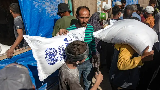 epa11693921 Palestinians carry bags of flour handed out by a United Nations Relief and Works Agency for Palestine Refugees in the Near East (UNRWA) aid distribution center in Khan Younis, southern Gaza Strip, 31 October 2024. According to the UN, at least 1.9 million people (or nine in ten people) across the Gaza Strip are internally displaced, including people who have been repeatedly displaced. Since October 2023, only about 11 percent of the Gaza Strip has not been placed under Israeli-issued evacuation orders, the UN aid coordination office OCHA said. EPA/HAITHAM IMAD