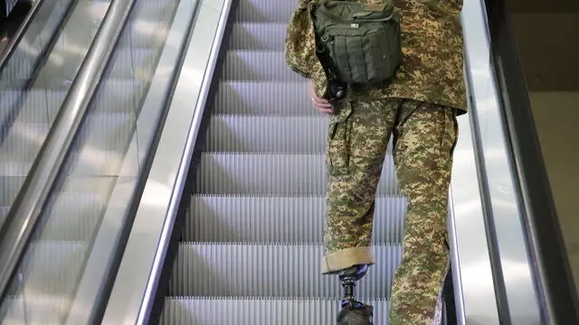 epaselect epa11403626 A participant with a prosthetig leg and wearing military camouflage stands on an escalator during the Ukraine Recovery Conference 2024 in Berlin, Germany, 11 June 2024. The Ukraine Recovery Conference 2024 takes place in Berlin from 11 to 12 June 2024, under the slogan 'United in defense. United in recovery. Stronger together.' EPA/CLEMENS BILAN