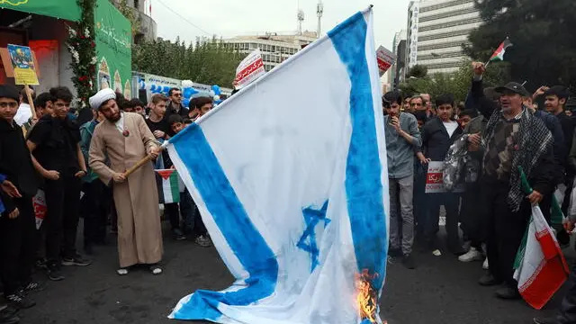 epa11698508 An Iranian cleric burns Israel's flag during an anti-US rally marking the 45th anniversary of the US Embassy takeover, in front of the former embassy building in Tehran, Iran, 03 November 2024. Iranian students occupied the embassy on 04 November 1979 after the USA granted permission to the late Iranian Shah to be hospitalized in the United States. Over 50 US diplomats and guards were held hostage by students for 444 days. The Iranian Supreme Leader Ayatollah Ali Khamenei said on 02 November that the US and Israel will definitely receive a harsh response following Israel's strike on Iran in October. EPA/ABEDIN TAHERKENAREH