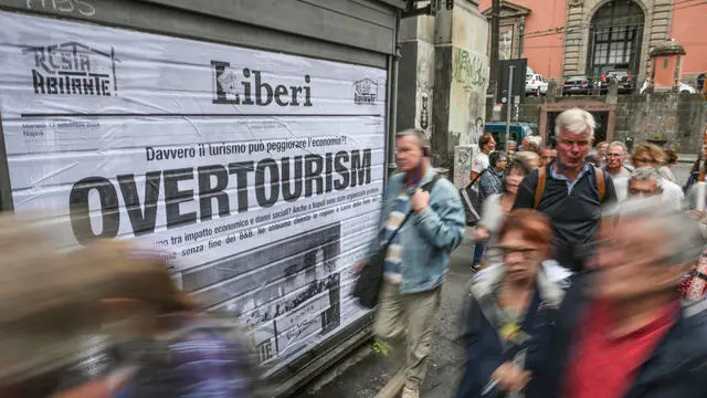 Il flash-mob degli attivisti della campagna 'Resta Abitante' a Napoli che a hanno affisso manifesti contro l' overtourism sulle serrande di una edicola dismessa, 17 settembre 2024 ANSA / CIRO FUSCO