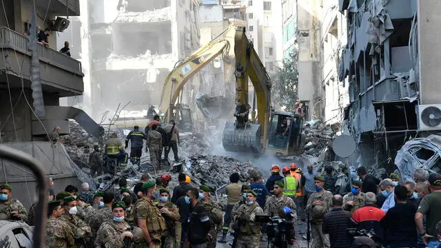 epa11735835 Armed soldiers stand guard as rescue teams, using excavators (rear), search for missing people under the rubble of a destroyed building after Israeli airstrikes hit a residential area in the Basta neighbourhood, central Beirut, Lebanon, 23 November 2024. At least 11 people were killed and 63 others injured after Israeli airstrikes hit a residential building in the Basta neighborhood in central Beirut, according to Lebanon's Ministry of Health. More than 3,640 people have been killed and more than 15,350 others injured in Lebanon since the escalation in hostilities between Israel and Hezbollah, the ministry said. EPA/ABBAS SALMAN