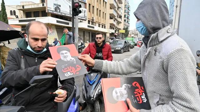 epa11743016 A man distributes leaflets with photos of late Hezbollah leader Hassan Nasrallah and Arabic inscription reading 'We will never be humiliated' after a ceasefire with Israel came into effect, in the Dahieh district in southern Beirut, Lebanon, 27 November 2024. On the evening of 26 November the US president confirmed that a ceasefire agreement between Israel and the Lebanese group Hezbollah - brokered by the United States and France - had been approved by Israel's cabinet and would come into effect at 02:00 GMT on 27 November. EPA/WAEL HAMZEH