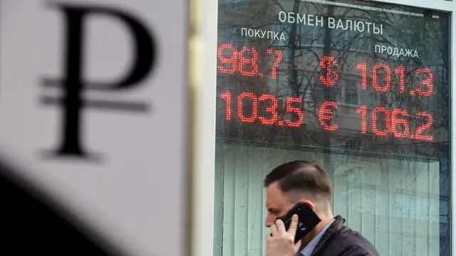 epa10897619 A man walks past an exchange office with an electronic panel displaying currency exchange rates for the US Dollar and Euro against the Russian ruble, in Podolsk, outside Moscow, 03 October 2023. The Russian ruble early on 03 October weakened further against the US Dollar, beyond a symbolic threshold of 100. The Central Bank of the Russian Federation exchange rate reached 99 rubles for one US Dollar and 104 rubles for one Euro, after the ruble recovered slightly. EPA/MAXIM SHIPENKOV