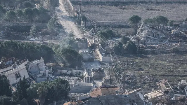 epa11753195 Israeli troops move between destroyed houses, in the south Lebanon village of Meiss El-Jabal, as they leave Lebanon on their way back into Israel, as seen from the Israeli side of the border, 02 December 2024. A 60-day ceasefire agreement between Israel and Hezbollah came into force on 27 November. EPA/ATEF SAFADI