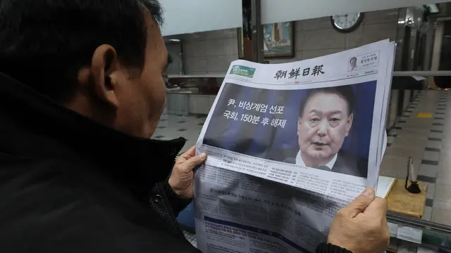 epaselect epa11755820 A man looks at a newspaper reporting South Korean President Yoon Suk Yeol announced his intention to lift the emergency martial law in Seoul, South Korea, 04 December 2024. President Yoon annnounced his intention to lift the emergency martial law hours after the National Assembly unanimously voted in favor of a resolution urging the president to withdraw the martial law during an emergency plenary session. Yoon had declared martial law the previous night, citing the need to root out pro-North Korean forces and uphold the constitutional order. EPA/HAN MYUNG-GU