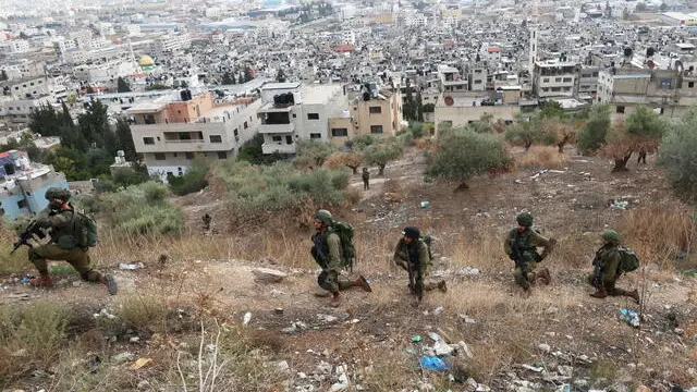 epa10983957 Israeli troops take position over Balata refugee camp during an operation by the Israeli army inside the camp, near Nablus, West Bank, 19 November 2023. According to the Palestinian Red Crescent, during the operation 12 people were injured, while two houses were demolished, the camp's administration said. More than 9,100 Palestinians and at least 1,400 Israelis have been killed, according to the Israel Defense Forces (IDF) and the Palestinian health authority, since Hamas militants launched an attack against Israel from the Gaza Strip on 07 October, and the Israeli operations in Gaza and the West Bank which followed it. EPA/ALAA BADARNEH