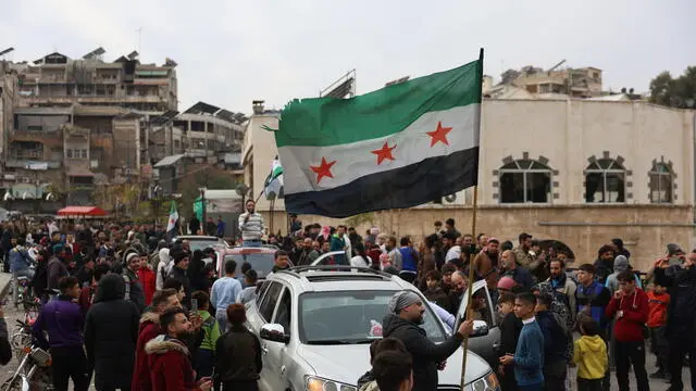 epa11762428 People wave a Syrian opposition flag after opposition fighters took control of the city of Hama, Syria, 07 December 2024. Syrian opposition forces, led by the Islamist militant group Hayat Tahrir al-Sham (HTS), launched an offensive on 27 November, triggering counterattacks by the Syrian regime forces as well as Russian and Syrian airstrikes on opposition-controlled areas. EPA/MOHAMMED AL RIFAI