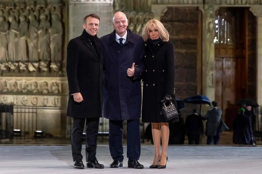 French President Emmanuel Macron (L) and his wife Brigitte (R) welcome FIFA President Gianni Infantino ahead of a ceremony to mark the re-opening of the landmark Notre-Dame Cathedral in central Paris on December 7, 2024. Around 50 heads of state and government are expected in the French capital to attend the ceremony marking the rebuilding of the Gothic masterpiece five years after the 2019 fire which ravaged the world heritage landmark and toppled its spire. Some 250 companies and hundreds of experts were part of the five-year restoration project at a cost of hundreds of millions of euros. (Photo by Christophe PETIT TESSON / POOL / AFP)