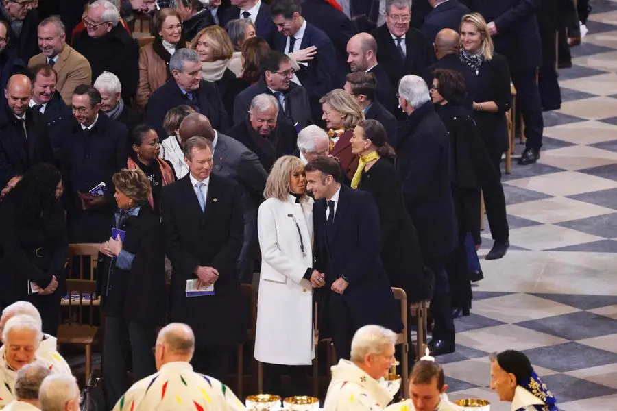 France's President Emmanuel Macron (front R) and France's firstlady Brigitte Macron (2nd R) speak as they attend the consecration of the new main altar designed by French artist and designer Guillaume Bardet, during the first mass for the public, at the Notre-Dame de Paris cathedral, in Paris, on December 8, 2024. Newly restored Notre Dame cathedral is set to hold its first service for the public on December 8, 2024 after a historic re-opening ceremony that saw firefighters, builders and artists celebrated for their work saving the 12th-century masterpiece. The beloved Paris monument nearly burned down in 2019, but has been renovated inside and fitted with a new roof and spire during a frenzied reconstruction effort since then. (Photo by Ludovic MARIN / AFP)