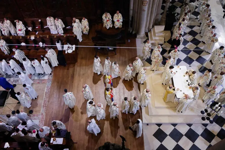 Members of the clergy receive a sacred host during the consecration of the new main altar designed by French artist and designer Guillaume Bardet, as part of the first mass for the public, at the Notre-Dame de Paris cathedral, in Paris, on December 8, 2024. Newly restored Notre Dame cathedral is set to hold its first service for the public on December 8, 2024 after a historic re-opening ceremony that saw firefighters, builders and artists celebrated for their work saving the 12th-century masterpiece. The beloved Paris monument nearly burned down in 2019, but has been renovated inside and fitted with a new roof and spire during a frenzied reconstruction effort since then. (Photo by Ludovic MARIN / AFP) / RESTRICTED TO EDITORIAL USE - MANDATORY MENTION OF THE ARTIST UPON PUBLICATION - TO ILLUSTRATE THE EVENT AS SPECIFIED IN THE CAPTION