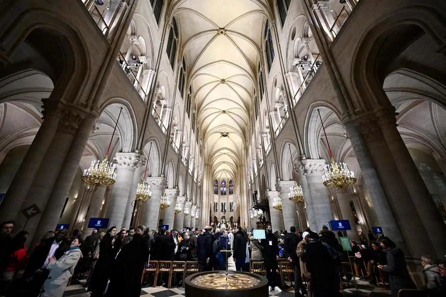 Devotees gather before the start of the first mass for the public in which Archbishop of Paris Laurent Ulrich will lead prayers to consecrate the new main alter, designed by French artist and designer Guillaume Bardet, at the Notre-Dame de Paris cathedral, in Paris on December 8, 2024. Newly restored Notre Dame cathedral is set to hold its first service for the public on December 8, 2024 after a historic re-opening ceremony that saw firefighters, builders and artists celebrated for their work saving the 12th-century masterpiece. The beloved Paris monument nearly burned down in 2019, but has been renovated inside and fitted with a new roof and spire during a frenzied reconstruction effort since then. (Photo by JULIEN DE ROSA / AFP)