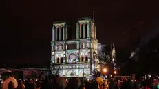 TOPSHOT - Crowds stand outside Notre-Dame Cathedral as it is illuminated during a ceremony to mark the re-opening of the landmark Cathedral, in central Paris, on December 7, 2024. Around 50 heads of state and government are expected in the French capital to attend the ceremony marking the rebuilding of the Gothic masterpiece five years after the 2019 fire which ravaged the world heritage landmark and toppled its spire. Some 250 companies and hundreds of experts were part of the five-year restoration project at a cost of hundreds of millions of euros. (Photo by Dimitar DILKOFF / AFP)