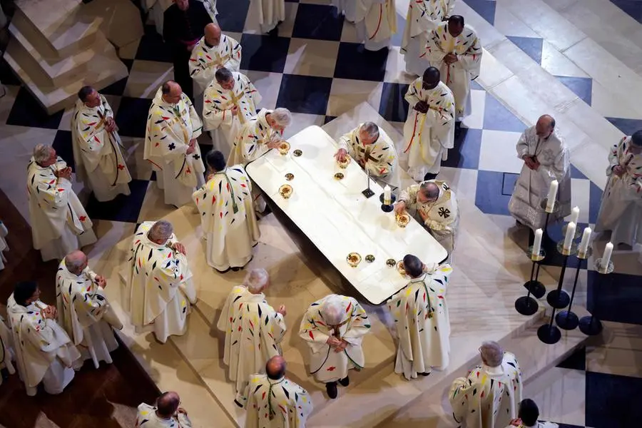 Members of the clery take part in prayers lead by the Archbishop of Paris Laurent Ulrich for the consecration of the new main altar, designed by French artist and designer Guillaume Bardet which replaces the old one that was destroyed in 2019, during a mass at the Notre-Dame de Paris cathedral, in Paris on December 8, 2024. Newly restored Notre Dame cathedral is set to hold its first service for the public on December 8, 2024 after a historic re-opening ceremony that saw firefighters, builders and artists celebrated for their work saving the 12th-century masterpiece. The beloved Paris monument nearly burned down in 2019, but has been renovated inside and fitted with a new roof and spire during a frenzied reconstruction effort since then. (Photo by Ludovic MARIN / AFP) / RESTRICTED TO EDITORIAL USE - MANDATORY MENTION OF THE ARTIST UPON PUBLICATION - TO ILLUSTRATE THE EVENT AS SPECIFIED IN THE CAPTION