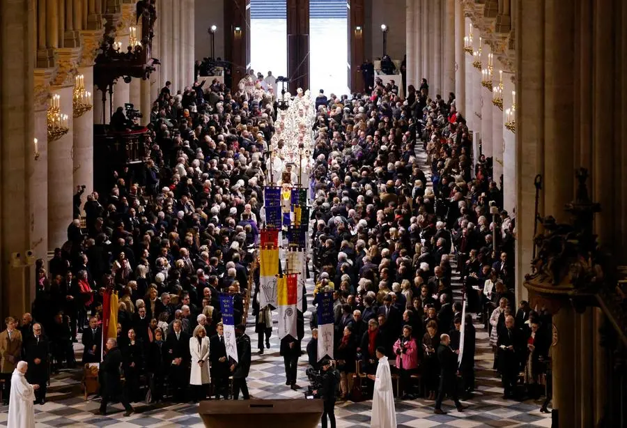 Members of the clergy and banner bearers walk towards the new main altar designed by French artist and designer Guillaume Bardet during its consecration, as part of the first mass for the public, at the Notre-Dame de Paris cathedral, in Paris, on December 8, 2024. Newly restored Notre Dame cathedral is set to hold its first service for the public on December 8, 2024 after a historic re-opening ceremony that saw firefighters, builders and artists celebrated for their work saving the 12th-century masterpiece. The beloved Paris monument nearly burned down in 2019, but has been renovated inside and fitted with a new roof and spire during a frenzied reconstruction effort since then. (Photo by Ludovic MARIN / AFP) / RESTRICTED TO EDITORIAL USE - MANDATORY MENTION OF THE ARTIST UPON PUBLICATION - TO ILLUSTRATE THE EVENT AS SPECIFIED IN THE CAPTION