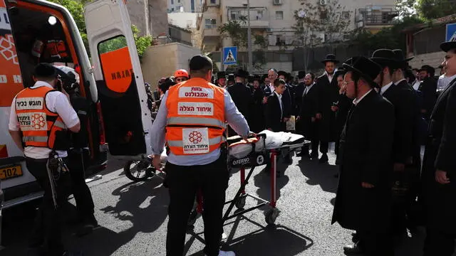 epa11293301 Israeli health personnel at work at the scene of a ramming attack in the ultra-Orthodox neighborhood of Jerusalem, 22 April 2024. Israeli police reported that three pedestrians were lightly injured when they were run over by a vehicle along Mordechai Tekhelet Street in Jerusalem. According to police, two individuals emerged from the vehicle and fled discarding their concealed weapons along the way. EPA/ATEF SAFADI