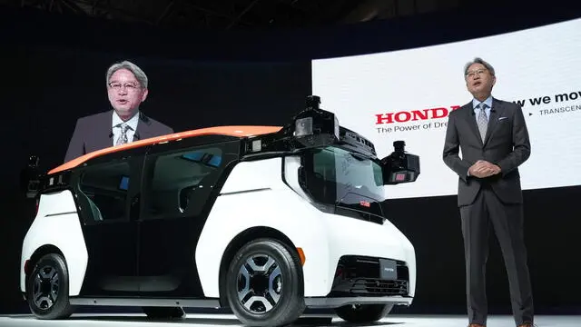 epa10937574 Toshihiro Mibe (R), President and CEO of Japanese carmaker Honda Motor Co., Ltd., unveils the self-driving vehicle 'Cruise Origin' during a presentation at the Japan Mobility Show 2023 in Tokyo, Japan, 25 October 2023. The Japan Mobility Show 2023 will be open to the general public from 28 October to 05 November 2023. Honda announced plans to launch a autonomous-driving taxi service using 'Cruise Origin' in Japan in early 2026 with GM Cruise. EPA/KIMIMASA MAYAMA