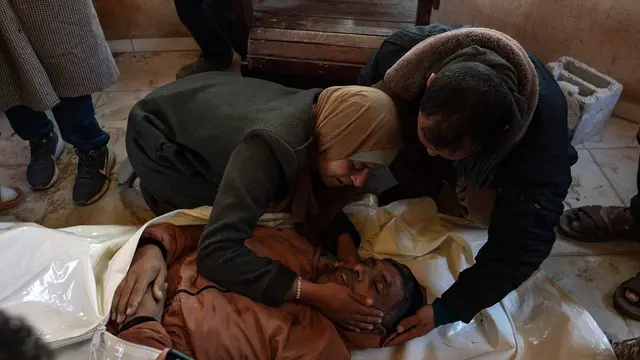 epa11771772 GRAPHIC CONTENT - Palestinians mourn next to the body of their relative who was killed in an Israeli airstrike, west of Khan Younis in the southern Gaza Strip, 12 December 2024. According to Nasser Hospital in Gaza, more than 12 Palestinians guarding humanitarian aid were killed in an Israeli airstrike west of Khan Younis. More than 45,000 Palestinians and over 1,400 Israelis have been killed, according to the Palestinian Health Ministry and the Israeli Army, since Hamas militants launched an attack against Israel from the Gaza Strip on 07 October 2023, and the Israeli operations in Gaza and the West Bank which followed it. EPA/HAITHAM IMAD -- ATTENTION EDITORS: GRAPHIC CONTENT --