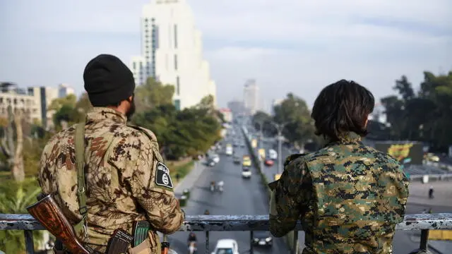 epa11770946 Two armed men keep watch over a road from a bridge in Damascus, Syria, 11 December 2024. Syria's Military Operations Administration announced on 11 December the lifting of the curfew imposed on Damascus and urged residents to return to their workplaces following the ouster of Syrian President al-Assad on 08 December. EPA/HASAN BELAL