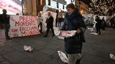 Alcuni aderenti ai comitati pro Palestina, hanno inscenato un flash mob sotto l'albero di Natale in piazza De Ferrari, con striscioni e teli bianchi sporchi di rosso a simboleggiare il sangue dei bambini morti a Gaza. Genova, 18 dicembre 2024. ANSA/LUCA ZENNARO