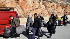 epa11776998 Syrians who have fled their country, including Shiite Muslims, walk with their belongings after they arrived from Syria, at the Al-Masnaa crossing as they prepare to enter Lebanon, on the Lebanese-Syrian border, Lebanon, 14 December 2024. Scores of Syrians who fled their country following the ousting of Syrian President Bashar al-Assad on 08 December, wait at the border crossing to enter Lebanon due to the unstable situation in their country. EPA/WAEL HAMZEH