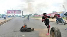 epa11760092 A man throws a burning tire from a barricade during a post-election protest in a street of Maputo, Mozambique, 06 December 2024. In recent weeks, supporters of former presidential candidate Venancio Mondlane, who is currently in exile, have taken to the streets of the Mozambican capital to challenge the results of the disputed general election held in October 2024. EPA/LUISA NHANTUMBO