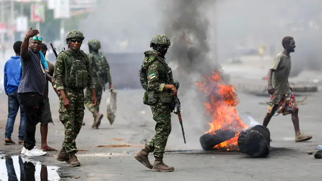 epa11760087 Military personnel pass by burning tires and barricades during a post-election protest, in a street of Maputo, Mozambique, 06 December 2024. In recent weeks, supporters of former presidential candidate Venancio Mondlane, who is currently in exile, have taken to the streets of the Mozambican capital to challenge the results of the disputed general election held in October 2024. EPA/LUISA NHANTUMBO