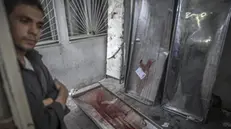 epa04340650 A Palestinian man stand next to bloodied gurneys in the morgue of the Kamal Adwan hospital in Beit Lahia, northern Gaza Strip, 04 August 2014. A seven-hour humanitarian ceasefire called by Israel went into effect in most of the Gaza Strip on 04 August after an attack that killed 10 people at a UN-run school. The temporary ceasefire was to last from 10 am (0700 GMT) until 5 pm in the entire enclave except for the area east of the town of Rafah in southern Gaza - a focal point of fighting since a botched attempt by Palestinian militants to snatch a soldier there on 01 August. EPA/OLIVER WEIKEN ATTENTION EDITORS: PICTURE CONTAINS GRAPHIC CONTENT