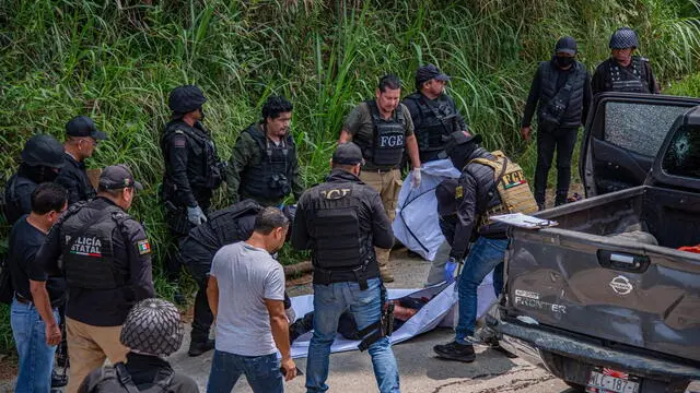 epa10671746 Members of the State Police and the State Attorney General's Office lift a corpse next to a truck with bullet holes, in the municipality of Chenalho, Chiapas state, Mexico, 03 June 2023. At least seven dead and three wounded in an armed attack a night earlier against victims of forced displacement from the Santa Martha sector, who took refuge in the Zapatista community of Polho, Chenalho municipality, in the Mexican state of Chiapas, reported the state authorities. EPA/Carlos Lopez ATTENTION: GRAPHIC CONTENT