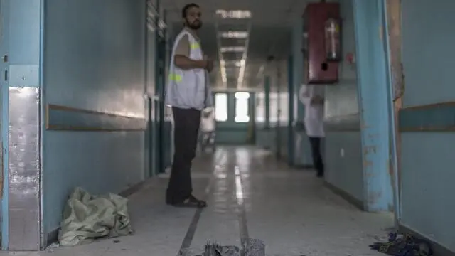 epa04317936 A staff member of the Al Wafa hospital in the Shuja'iyya neighbourhood in east Gaza City looks at the remains of an Israeli Defense Forces warning missile, 16 July 2014. The hospital which is located only a few kilometres away from the border to Israel received according to senior staff members several warning missiles and phone calls from Israeli Defense Forces in the past days urging them to evacuate the hospital immediately before it would be destroyed. Foreign activists have gathered in the only rehabilitation hospital in the Gaza Strip to act as human shield for the remaining 14 patients in Al Wafa. EPA/OLIVER WEIKEN