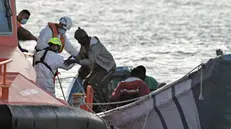 epa11794130 Members of the Spanish 'Salvamento Maritimo' safe and rescue brigade help migrants upon their arrival at La Restinga port in El Hierro, Canary Islands, Spain, 26 December 2024. Three small dugout boats carrying 196 people have arrived in the Canary Islands in the last few hours. EPA/GELMERT FINOL