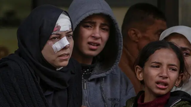 epa11774380 Palestinians, among them an injured woman, mourn near the bodies of their relatives killed after an Israeli air strike, in Al Nuseirat refugee camp, central Gaza Strip, 13 December 2024. According to the Palestinian Ministry of Health in Gaza, at least 40 Palestinians were killed in an overnight Israeli airstrike in Al Nusairat refugee camp, central Gaza. More than 45,500 Palestinians and over 1,400 Israelis have been killed, according to the Palestinian Health Ministry and the Israeli Army, since Hamas militants launched an attack against Israel from the Gaza Strip on 07 October 2023 and the Israeli operations in Gaza and the West Bank that followed it. EPA/MOHAMMED SABER