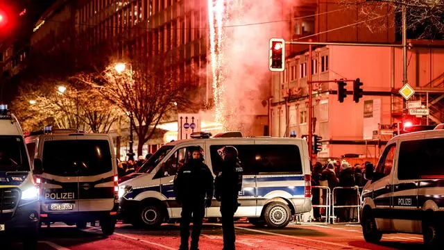 epa11800397 Fireworks illuminate the sky behind police cars during New Year's Eve celebrations in Berlin, Germany, 31 December 2024. EPA/FILIP SINGER