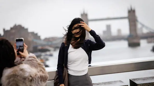 epaselect epa11738472 A woman poses for a photo on the London Bridge on a windy day in London, Britain, 24 November 2024. National severe weather warnings are still in place across the UK as Storm Bert already brought strong winds, heavy rain and snow across much of the UK, according to the Met Office. EPA/TOLGA AKMEN