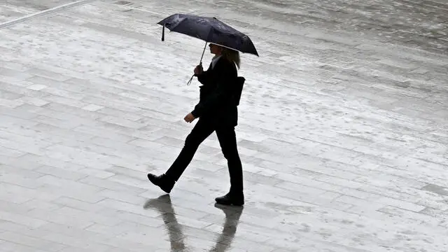 Una ersona passeggia riparandosi dalla pioggia con un ombrello per l'intensa pioggia, Milano, 24 ottobre 2023. Fino al weekend due perturbazioni raggiungeranno l'Italia e la prima, la più forte, è già in atto in queste ore. Da oggi fino al fine settimana, dunque, l'Italia verrà raggiunta da due perturbazioni, con venti di Libeccio con raffiche fino a 70-80 km/h. Ci saranno mareggiate sulle coste esposte e il Mar Ligure sarà agitato, mossi o molto mossi gli altri bacini. ANSA/DANIEL DAL ZENNARO