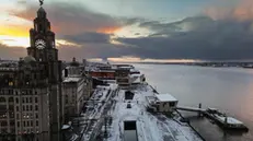 epa11810780 An aerial photograph taken by drone shows the sun rising behind the Royal Liver building after snow fell overnight in Liverpool, Britain, 07 January 2025. The Met Office has issued further yellow warnings for snow and ice across Northern Ireland and the west coast of Britain after heavy snowfall and rain caused widespread travel disruption and flooding. EPA/ADAM VAUGHAN