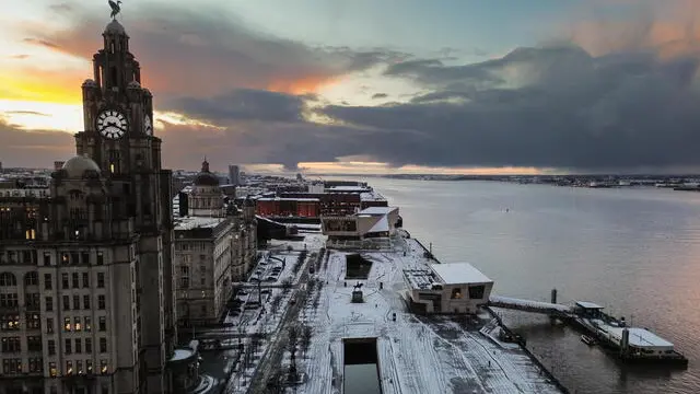 epa11810780 An aerial photograph taken by drone shows the sun rising behind the Royal Liver building after snow fell overnight in Liverpool, Britain, 07 January 2025. The Met Office has issued further yellow warnings for snow and ice across Northern Ireland and the west coast of Britain after heavy snowfall and rain caused widespread travel disruption and flooding. EPA/ADAM VAUGHAN