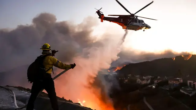 epaselect epa11812314 Los Angeles County firefighters using hoses and water drops from a helicopter battle the Palisades wildfire in Pacific Palisades, California, USA, 07 January 2025. According to the National Weather Service, large portions of the Los Angeles area are under extreme wildfire risk from 07 to 08 January due to high winds and dry conditions. EPA/CAROLINE BREHMAN