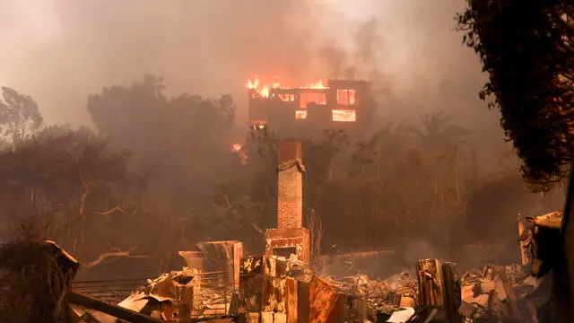 epa11813471 A house on fire and the remains of another burnt home in an area affected by the Palisades wildfire in Malibu, California, USA, 08 January 2025. According to data from California Department of Forestry and Fire Protection, CAL FIRE, the Palisades fire has burned through thousands of acres and has forced tens of thousands of evacuations in the Los Angeles area. EPA/ALLISON DINNER