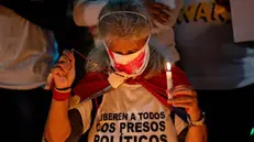 epa11752658 A mother holds a candle and a rosary during a vigil in Caracas, Venezuela, 01 December 2024. Relatives and friends of those considered ''political prisoners'', accompanied by activists and other citizens, held a vigil in a Caracas square to demand the release of the detainees, as well as the ''cessation of repression'' in the country. EPA/RONALD PENA