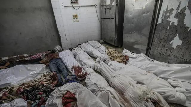 epa11648583 Bodies wrapped in blankets lie inside the morgue of the Al Aqsa Martyrs Hospital following an early morning Israeli airstrike on the Al Bureij refugee camp, in Deir Al Balah town, central Gaza Strip, 08 October 2024. More than 41,900 Palestinians and over 1,400 Israelis have been killed, according to the Palestinian Health Ministry and the Israel Defense Forces (IDF), since Hamas militants launched an attack against Israel from the Gaza Strip on 07 October 2023, and the Israeli operations in Gaza and the West Bank which followed it. EPA/MOHAMMED SABER ATTENTION EDITORS: GRAPHIC CONTENT