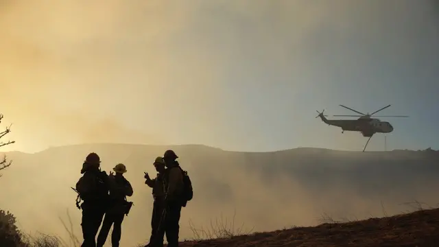 epa11816100 A helicopter drops water on the Kenneth wildfire in the Woodland Hills neighborhood of Los Angeles, California, USA, 09 January 2025. According to the California Governor's office, more than 7,500 firefighting and emergency personnel are involved in response efforts, as multiple wildfires are burning across thousands of acres and have forced widespread evacuations in the Los Angeles area. EPA/ALLISON DINNER