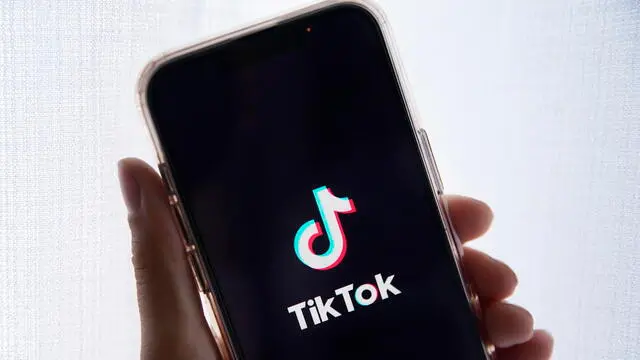 epa10635388 In this photo illustration a person holds up a cell phone with the TikTok logo displayed in Los Angeles, California, USA, 17 May 2023. Govenor Greg Gianforte of Montana signed a measure that bans the TikTok app in the state. EPA/CAROLINE BREHMAN