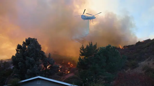 epa11819202 A helicopter does a water drop over a home during the Palisades wildfire in Los Angeles, California, USA, 11 January 2025. Thousands of firefighting and emergency personnel are involved in response efforts, as multiple wildfires are continuing to burn across thousands of acres in Southern California, destroying thousands of homes and forcing people to evacuate areas throughout the Los Angeles area. EPA/ALLISON DINNER