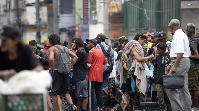 epa10794130 Homeless people and drug addicts stand in an area known as 'Cracolandia' in the center of Sao Paulo, Brazil 10 August 2023. The term 'Cracolandias' refers to areas with high levels of street-based homelessness and public drug use, located in various Brazilian cities. Dozens of merchants in downtown Sao Paulo lowered their stores' blinds on 10 August to protest about having become neighbors of the highest concentration of drug users in the city. EPA/Sebastiao Moreira