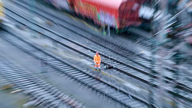 epa11215047 A slow exposure with zoom effect picture shows a railway worker stands on empty tracks during a German Train Drivers' Union (GDL) strike at a Cargo station in Hagen, Germany, 11 March 2024. The GDL called on its members to strike starting 6:00 pm on 11 March for freight trains and 2:00 am on 12 March for passenger trains for 24 hours, over a wages dispute with German railway company Deutsche Bahn (DB). EPA/CHRISTOPHER NEUNDORF