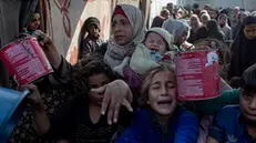 epa11816525 Palestinians, including children, hold metal pots and pans as they gather to receive food cooked by a charity kitchen, in Khan Yunis, southern Gaza Strip, 10 January 2025. According to the UN Palestinian refugee agency UNRWA, over 1.8 million people across the Gaza Strip are experiencing 'high levels' of acute food insecurity, with acute malnutrition ten times higher than before the war. According to the UN, at least 1.9 million people, about 90 percent of the population, across the Gaza Strip are internally displaced, including people who have been repeatedly displaced. EPA/HAITHAM IMAD