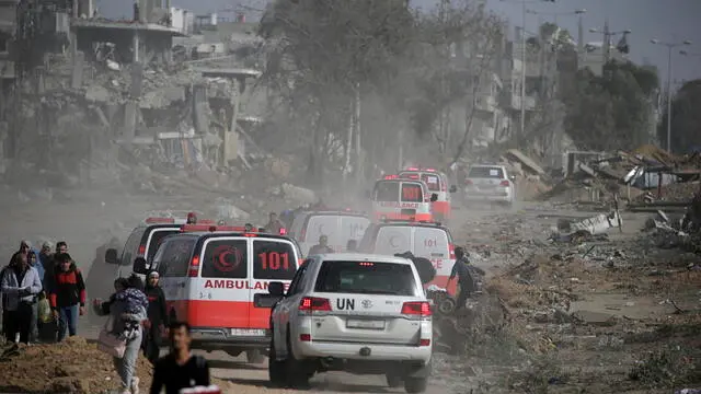 epa10996189 A convoy of Red crescent and UN vehicles drives past Palestinians as they cross from the northern Gaza Strip to the southern Gaza Strip as Israeli tanks (not pictured) move along Salah Al Din road, in the central Gaza Strip, 26 November 2023. After Israel and Hamas agreed to a four-day ceasefire, mediated by Qatar, the US, and Egypt, that came into effect at 05:00 AM GMT on 24 November, some Palestinians who were still in central Gaza moved towards the south while others already displaced in the south went back to the northern part to check on relatives they had left behind and on their homes to collect salvageable belongings. As part of the ceasefire, the agreement included that 50 Israeli hostages, women and children, are to be released by Hamas. 150 Palestinian women and children that were detained in Israeli prisons are to be released in exchange. EPA/MOHAMMED SABER